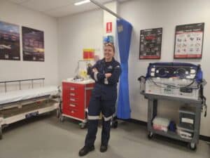 RFDS Flight Nurse Maddie stands in a medical bay at our Essendon hangar; equipment including a stretcher and humidicrib are visible behind her.