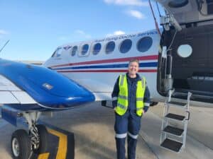 RFDS Flight Nurse Maddie smiles brightly as she stands beside RFDS Victoria's B350 aircraft.